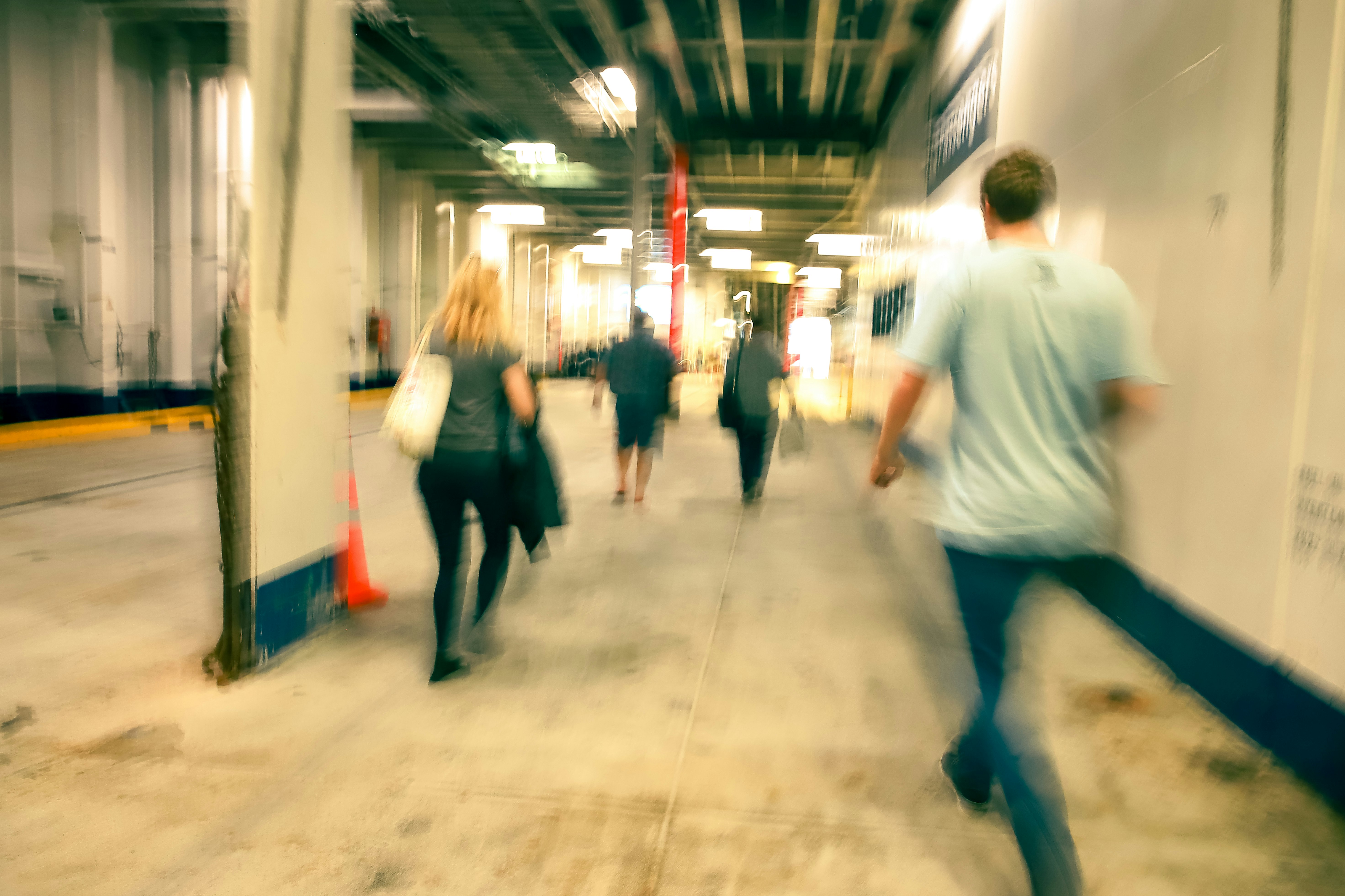 man in white t-shirt and blue denim jeans walking on hallway